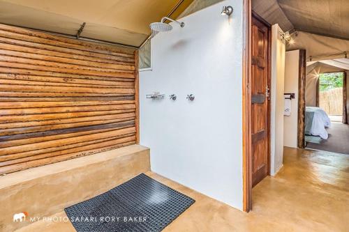 Zimmer mit einer Dusche und einer Holzwand in der Unterkunft Utshwayelo Kosi Bay Mouth Lodge & Camp in Manguzi