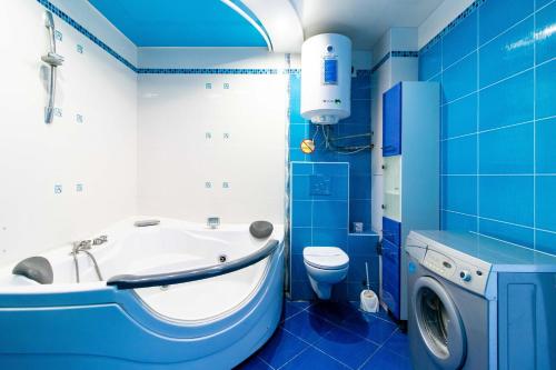 y baño azul con bañera y lavadora. en Kvartirkoff na Obolonskom 40, en Kiev