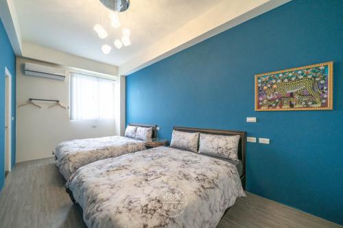 ein Schlafzimmer mit 2 Betten und einer blauen Wand in der Unterkunft Jingchao B&B in Zhuangwei