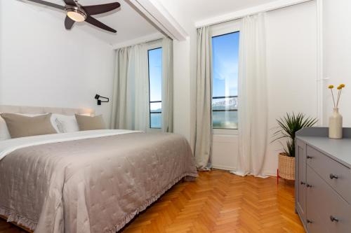 a white bedroom with a bed and large windows at Cozy apartment with a beautiful view in Split