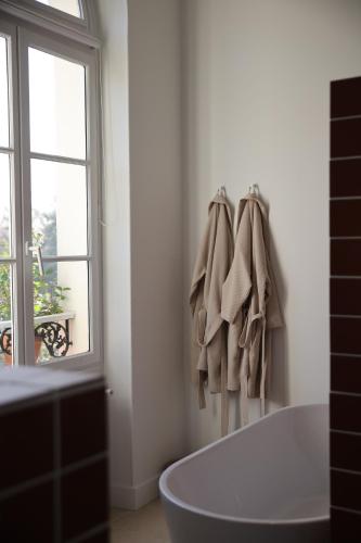 a white bathroom with a bath tub and a window at Lomalia in Parmain