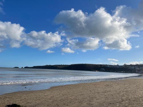 a beach with a cloudy sky and the ocean at Stylish Saundersfoot Top Floor 2-Bed Seaview Apartment, Balcony & Parking in Pembrokeshire