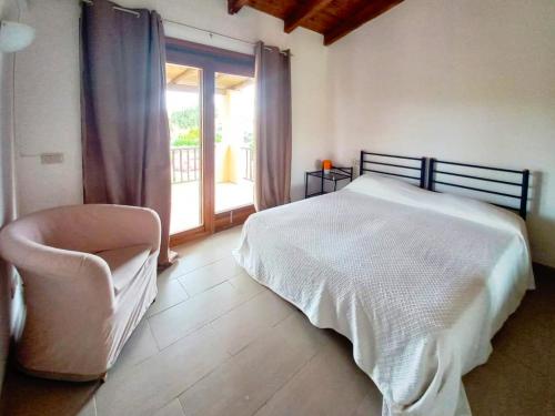 a bedroom with a bed and a chair and a window at Villa Serena A in Stintino