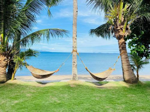 two hammocks hanging between two palm trees on a beach at Badladz Beach and Dive Resort in Puerto Galera