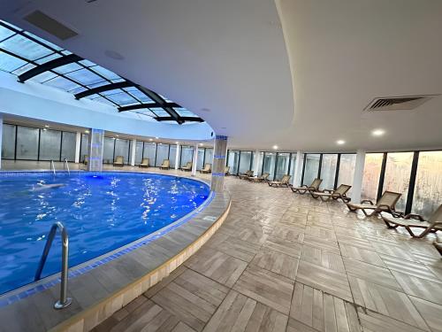 a large swimming pool in a building with chairs at PANORAMA ORBI City Center Suite Sea View in Batumi