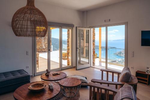 a living room with tables and chairs and sliding glass doors at Melianthos Villas in Vathi, Sifnos