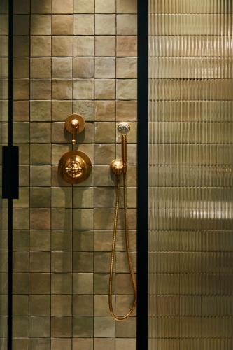 a shower with a hose on a tiled wall at No.124 by GuestHouse, Brighton in Brighton & Hove