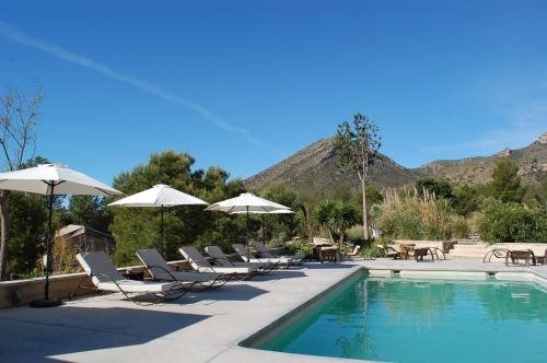 a pool with chairs and umbrellas next to a mountain at Awa Natura in Aigues