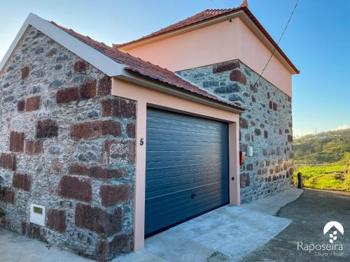 eine Garagentür an der Seite eines Backsteingebäudes in der Unterkunft Raposeira Country House in Calheta