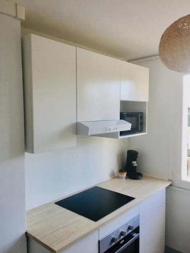 une cuisine avec des armoires blanches et un comptoir dans l'établissement Superbe T4 ensoleillé avec balcon à Avignon, à Avignon