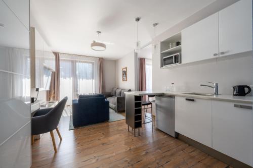 a kitchen with white cabinets and a living room at Hotel Willa Pod Skocznią in Zakopane