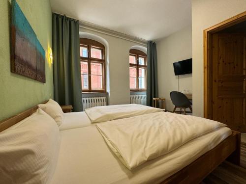 a bedroom with two white beds and two windows at Gaststätte Brauhaus Zwickau GmbH in Zwickau