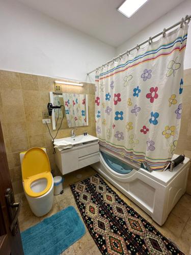 a bathroom with a yellow toilet and a shower curtain at Baka Bauhaus Studio in Jerusalem