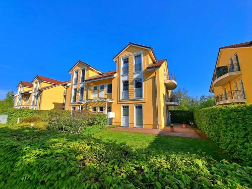 una gran casa amarilla en un césped verde en Schloonseevillen Bansin, en Bansin