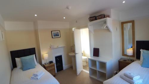 a bedroom with two beds and a bathroom at Charnwood Guest House in Lyme Regis