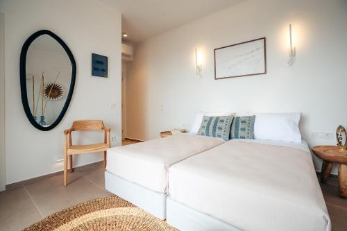 a white bed in a room with a mirror at Melianthos Villas in Vathi, Sifnos