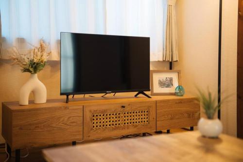 a flat screen tv sitting on top of a wooden entertainment center at KOISI Renovated traditional Japanese house 12min walk fm広島駅 Max5ppl 3LDK in Hiroshima