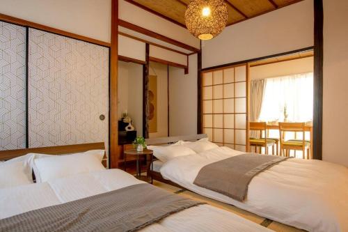 a bedroom with two beds and a table with chairs at 広島駅北口 古民家House 一軒家貸切り 自転車2台レンタル無料 in Hiroshima