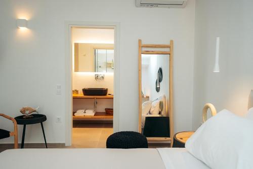 a bedroom with a white bed and a mirror at Melianthos Villas in Vathi, Sifnos