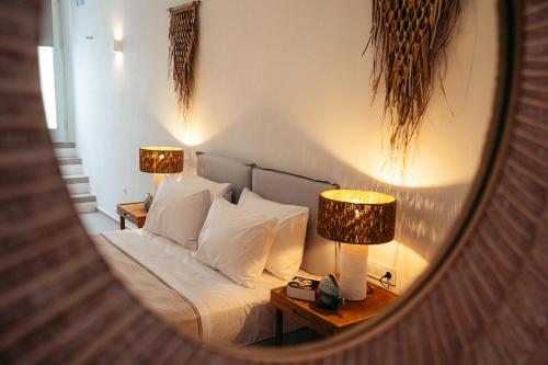 a bedroom with a bed with two lamps and a mirror at Melianthos Villas in Vathi, Sifnos