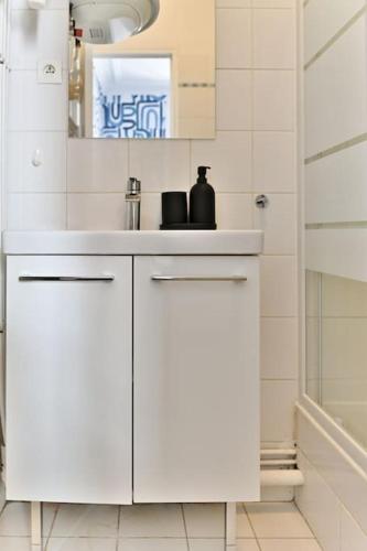 une salle de bain blanche avec un lavabo et une douche dans l'établissement Appartement Paisible Centre de Paris - Bleu, à Paris