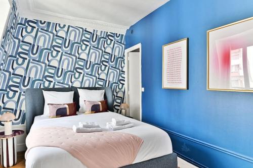 une chambre avec un grand lit avec un mur bleu dans l'établissement Appartement Paisible Centre de Paris - Bleu, à Paris