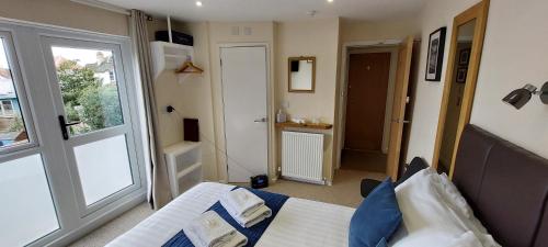 a bedroom with a bed and a window and a door at Charnwood Guest House in Lyme Regis