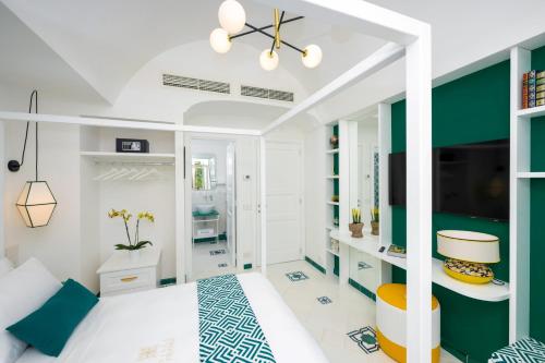 una camera con letto bianco e parete con accento verde di AMORE RENTALS - Villa Blu a Praiano