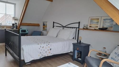 a bedroom with a large bed and a chair at studio B&B Zeeuws licht in Westkapelle