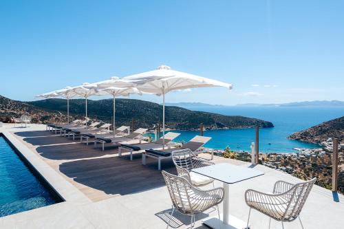 a pool with tables and chairs and the ocean at Melianthos Villas in Vathi, Sifnos