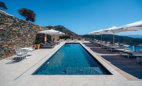 a swimming pool with chairs and umbrellas on a resort at Melianthos Villas in Vathi, Sifnos