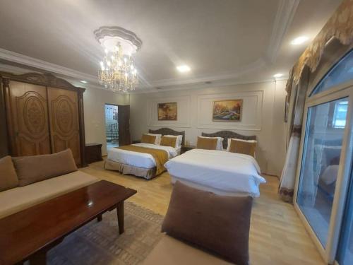 une chambre d'hôtel avec deux lits et un canapé dans l'établissement ڤيلا فاخرة لك بجميع الخدمات بالساحل الشمالي, à Qaryat Shākūsh