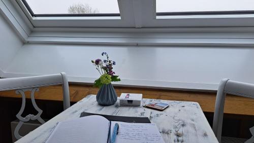 a table with a vase of flowers and a window at studio B&B Zeeuws licht in Westkapelle