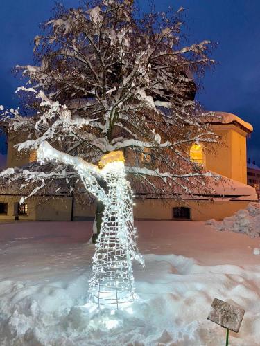 a sculpture of a person in the snow next to a tree at Alba Apartmany Železná Ruda in Železná Ruda