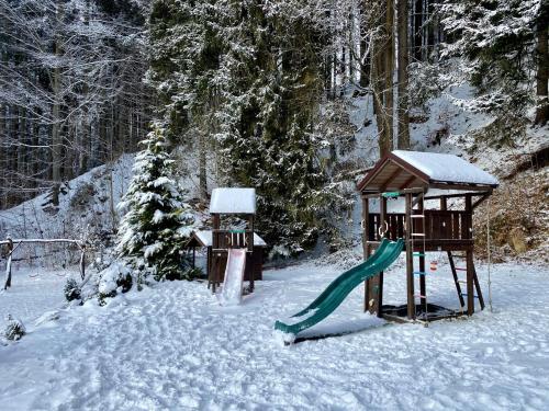 a playground in the snow with a slide at Alba Apartmany Železná Ruda in Železná Ruda