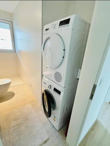 uma máquina de lavar e secar roupa numa pequena casa de banho em Brand New Luxury Studio in Belair with balcony em Luxemburgo