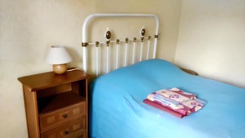 ein kleines Schlafzimmer mit einem blauen Bett und einem Nachttisch in der Unterkunft Maison d'une chambre avec wifi a Saint Pere in Saint-Père