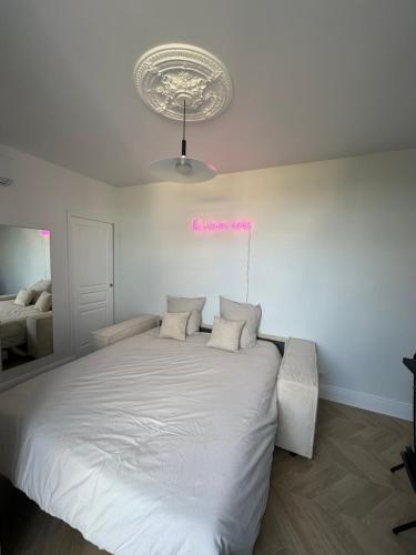 ein Schlafzimmer mit einem weißen Bett mit einem rosa Schild an der Wand in der Unterkunft Appartement, bel aperçu Tour Eiffel in Rueil-Malmaison