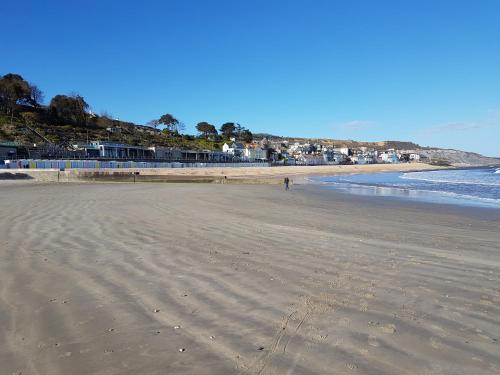 a beach with a person walking on the sand at Charnwood Guest House in Lyme Regis