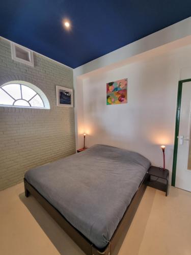 een slaapkamer met een bed in een kamer met een raam bij Studio Blank - Arthouse in Den Oever