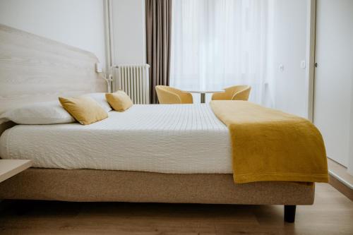 a bedroom with a bed with a yellow blanket on it at Hotel Venezia in Trento