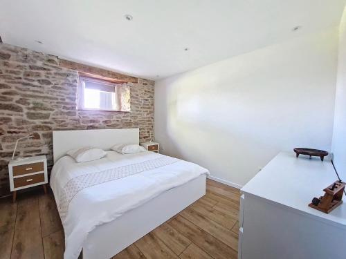 1 dormitorio con cama blanca y pared de ladrillo en Ancienne Bergerie Rénovée , Proche des Lacs, Sentiers Pédestres, en Comps-la-Grand-Ville