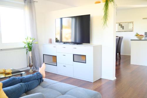 a person laying on a couch in a living room with a tv at Naturidyll am See in Fußach
