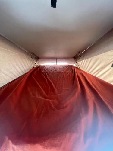 Tienda de campaña con una sábana roja en el techo en Camper car in underground parking en Barcelona