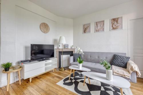 un salon avec un canapé et une télévision dans l'établissement T2 à 100m du centre - 10 min de Paris - 400m du lac et Casino d'Enghien - Gare d'Enghien à 10m, à Enghien-les-Bains