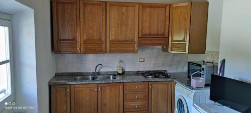 uma cozinha com armários de madeira e um lavatório em Casa Lucia em Cupra Marittima