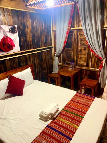 a bedroom with a large white bed with wooden walls at Puluong Bao Gia Homestay in Làng Bang