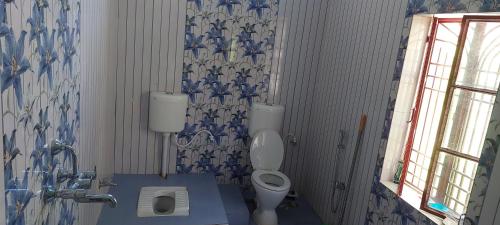 a bathroom with a toilet and blue and white wallpaper at Anand Bhavan in Deoghar