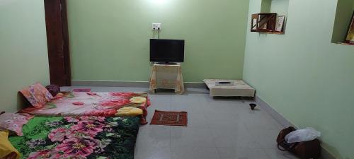 een kamer met een bed en een flatscreen-tv bij Anand Bhavan in Deoghar