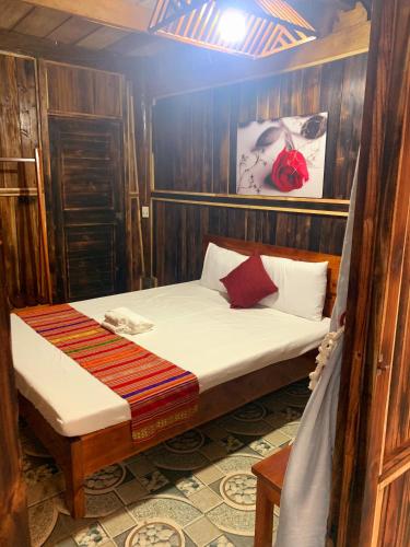 a small bed in a room with wooden walls at Puluong Bao Gia Homestay in Làng Bang